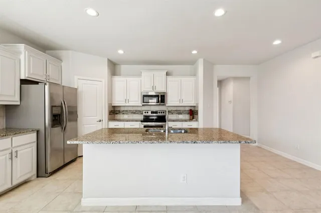 a large kitchen with stainless steel appliances granite countertop a stove a refrigerator a sink and dishwasher