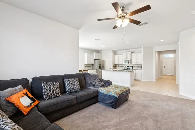 a living room with furniture kitchen view and a chandelier