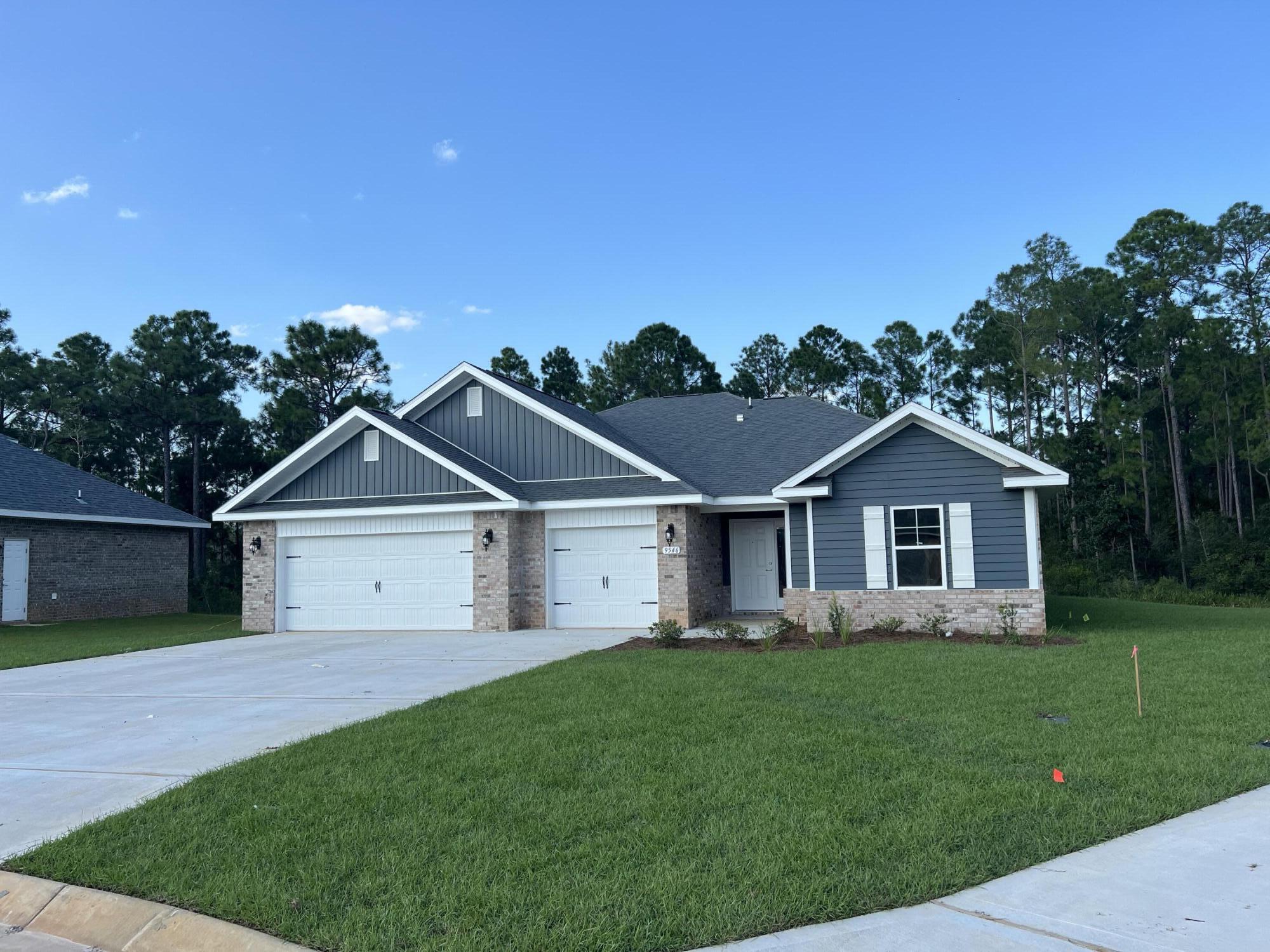 9546 Creets Landing Drive, Unit CL03 Navarre, FL 32566 - Photo 1 of 4 a front view of a house with a garden and yard