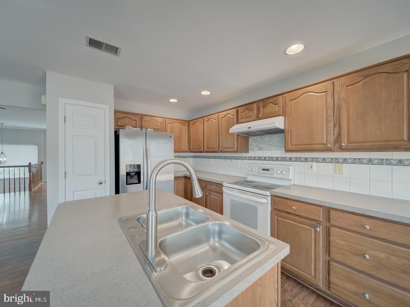 8241 Humphrey Lane Manassas, VA 20109 - Photo 19 of 55 a kitchen with stainless steel appliances granite countertop a sink a stove and white cabinets with wooden floor