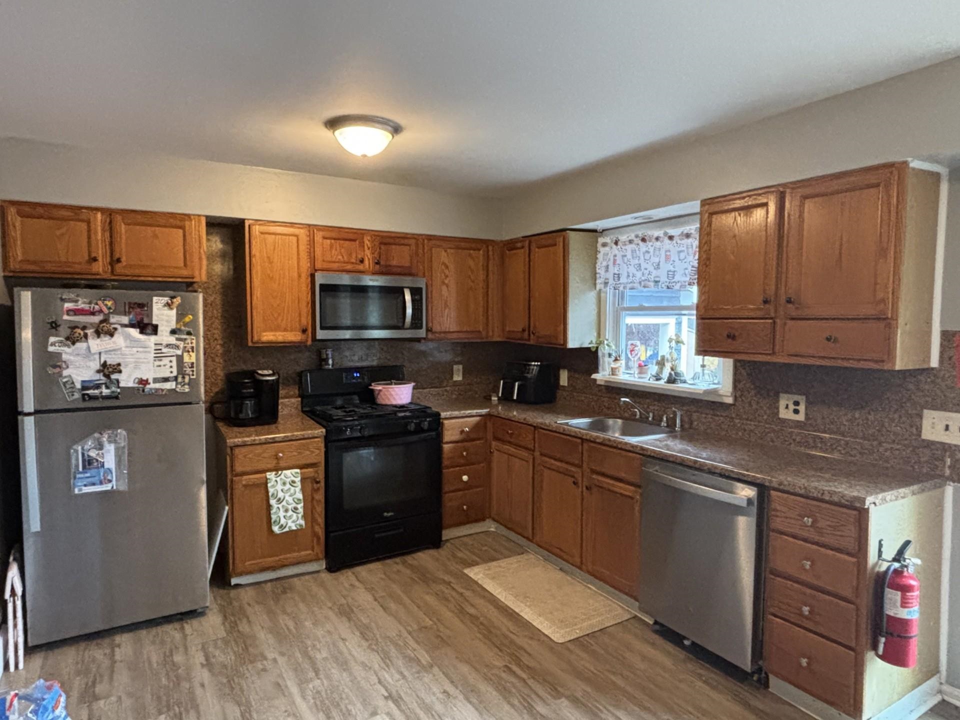 a kitchen with stainless steel appliances granite countertop a stove a sink dishwasher and a microwave oven with cabinets