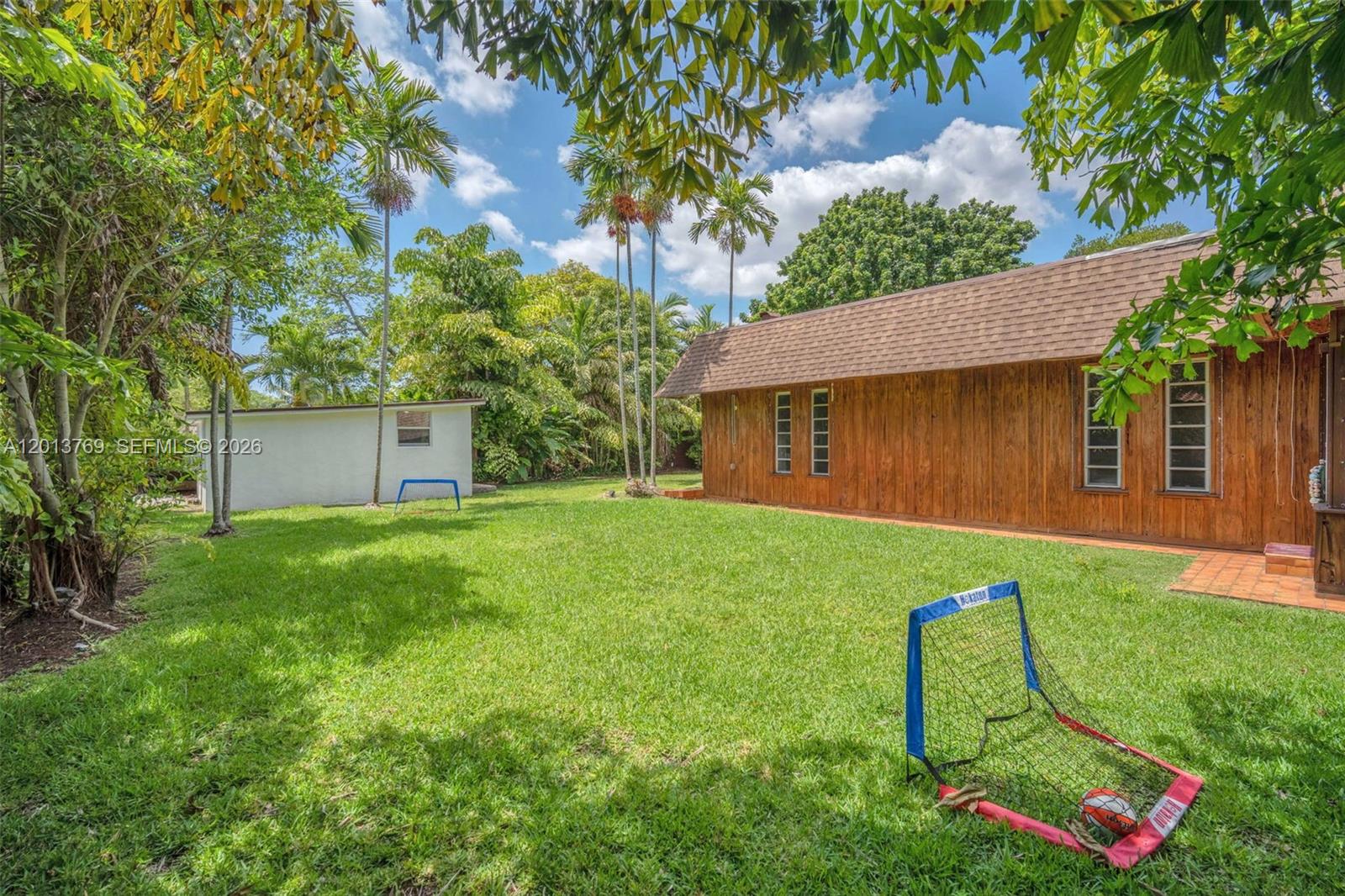 470 Northeast 113th Street, Unit 1 Miami, FL 33161 - Photo 50 of 56 a view of a backyard with table and chairs plants and large tree