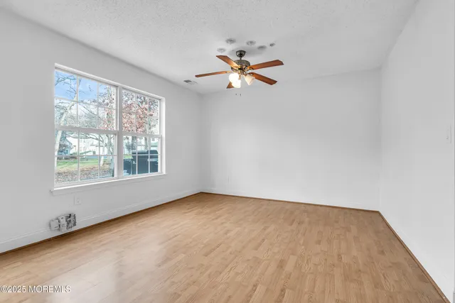 an empty room with a window and a fan