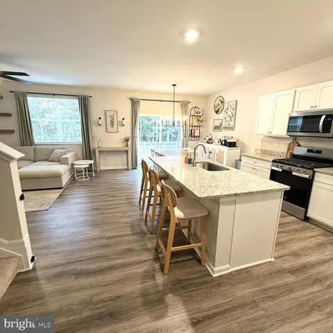 a open kitchen with stainless steel appliances granite countertop a stove a refrigerator a dining table and chairs with wooden floor