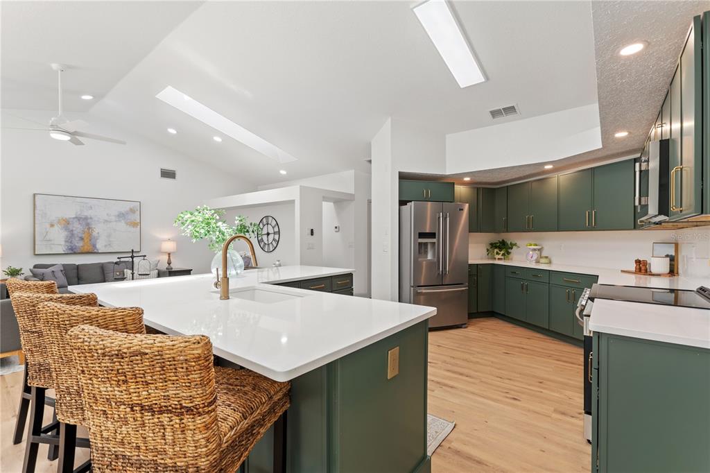 419 Silas Court Spring Hill, FL 34609 - Photo 15 of 56 a kitchen with stainless steel appliances kitchen island granite countertop a refrigerator a stove top oven a sink dishwasher and couches with wooden floor