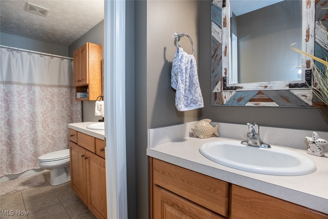 632 Rundle Street Lagrange, OH 44050 - Photo 23 of 30 Bathroom featuring vanity, a textured ceiling, light tile patterned floors, and a shower with shower curtain
