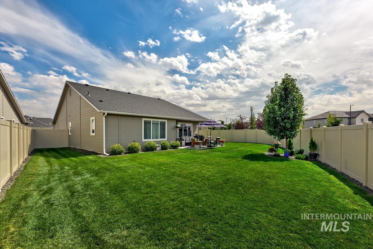 348 West Radiant Rdg Drive Meridian, ID 83642 - Photo 29 of 36 Expansive green lawn with a privacy fence, mature trees, and a paved patio area