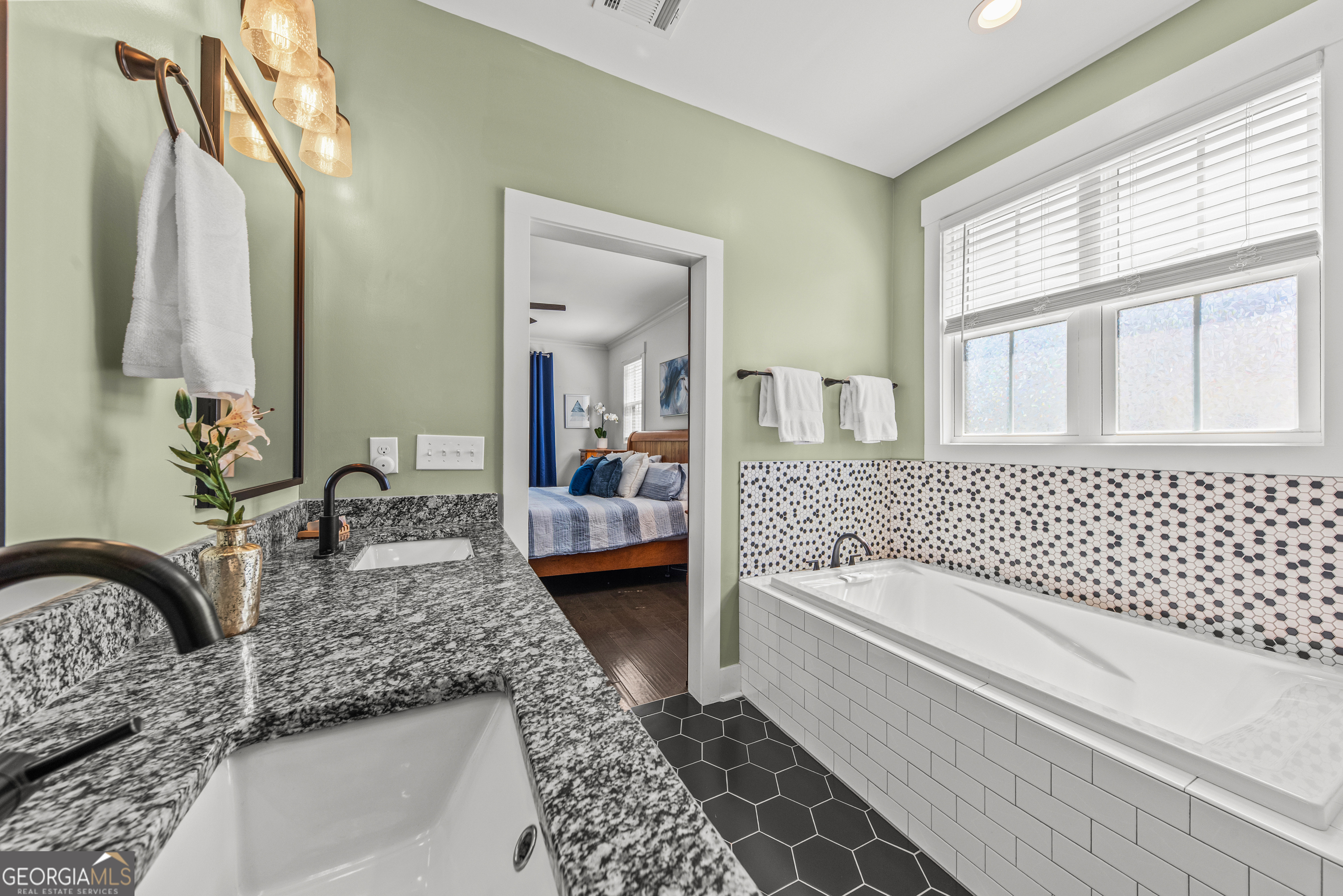 1100 West Magnolia Loop Madison, GA 30650 - Photo 22 of 40 a bathroom with a granite countertop tub a sink and a large mirror next to a window