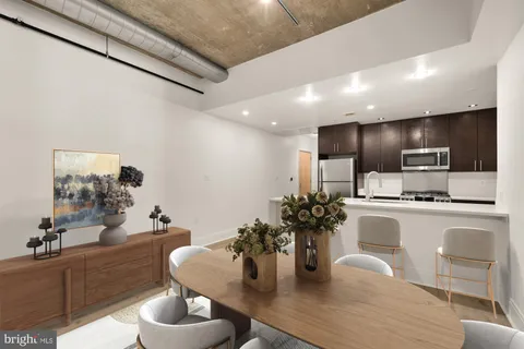 a kitchen with stainless steel appliances kitchen island granite countertop a sink dishwasher a dining table and chairs with wooden floor