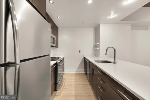 a kitchen with stainless steel appliances a refrigerator sink and white cabinets