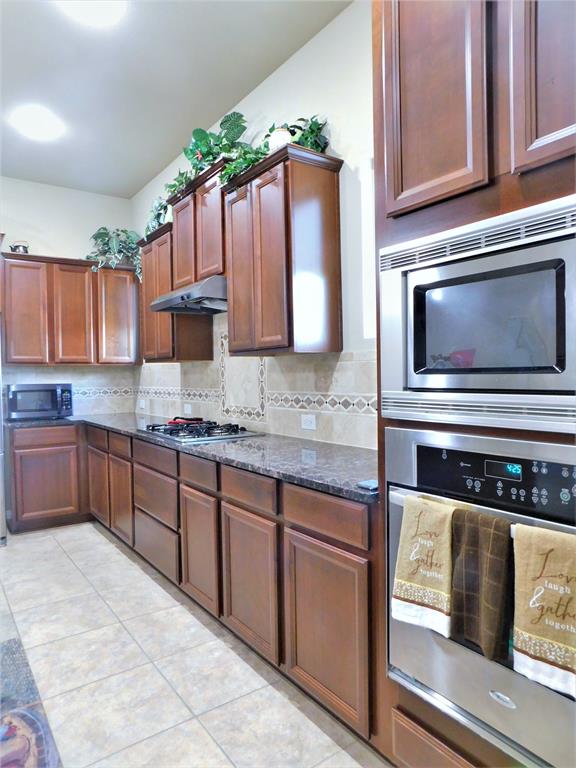 7712 Sweetgate Lane Denton, TX 76208 - Photo 11 of 40 a kitchen with stainless steel appliances granite countertop a sink stove and microwave