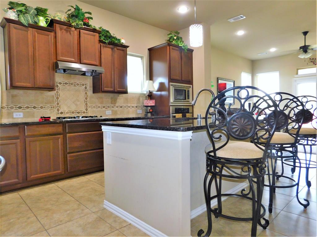 7712 Sweetgate Lane Denton, TX 76208 - Photo 12 of 40 a kitchen with stainless steel appliances a table chairs refrigerator and sink