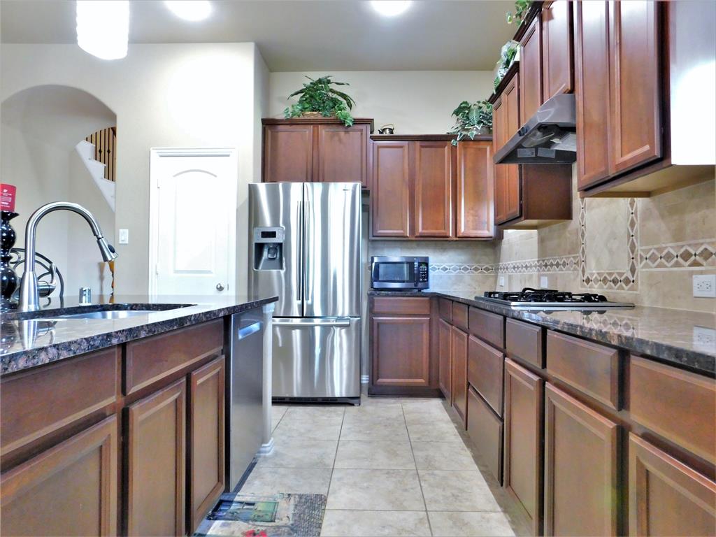 7712 Sweetgate Lane Denton, TX 76208 - Photo 13 of 40 a kitchen with stainless steel appliances granite countertop a refrigerator sink and cabinets