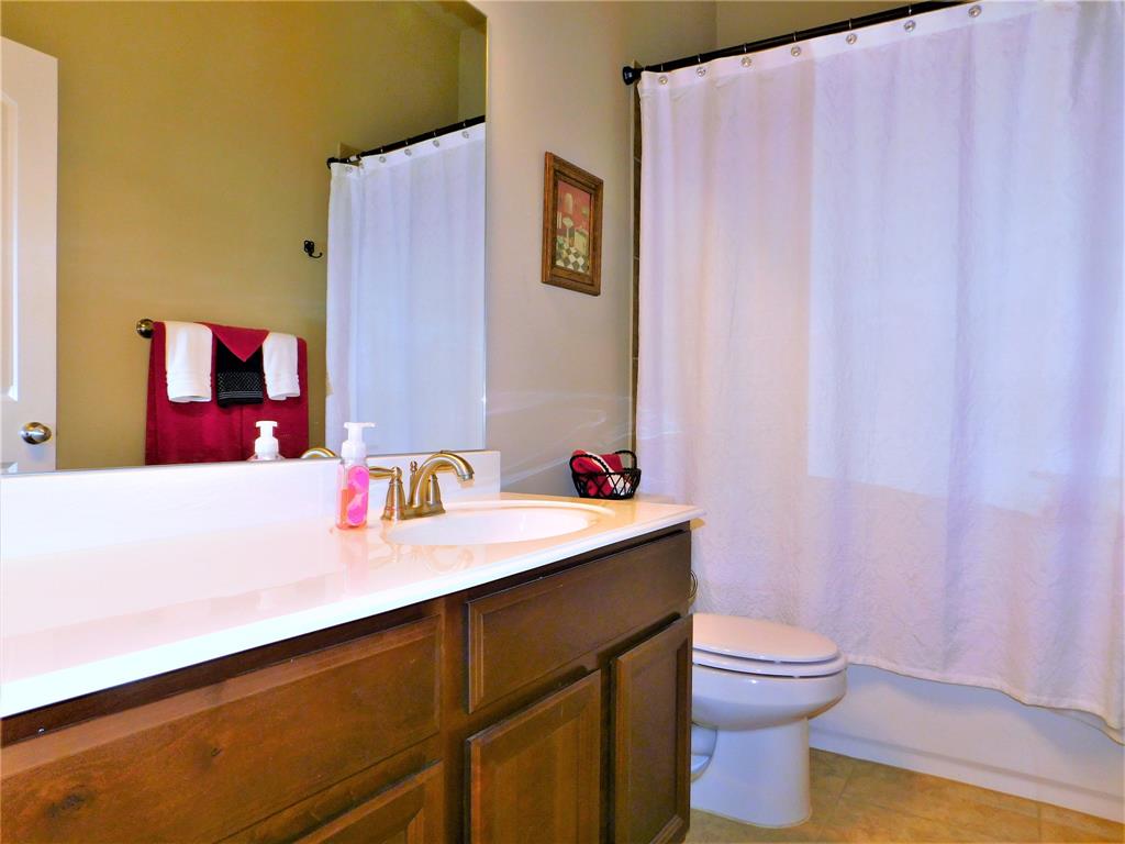 7712 Sweetgate Lane Denton, TX 76208 - Photo 25 of 40 a bathroom with a sink a toilet and a shower curtain