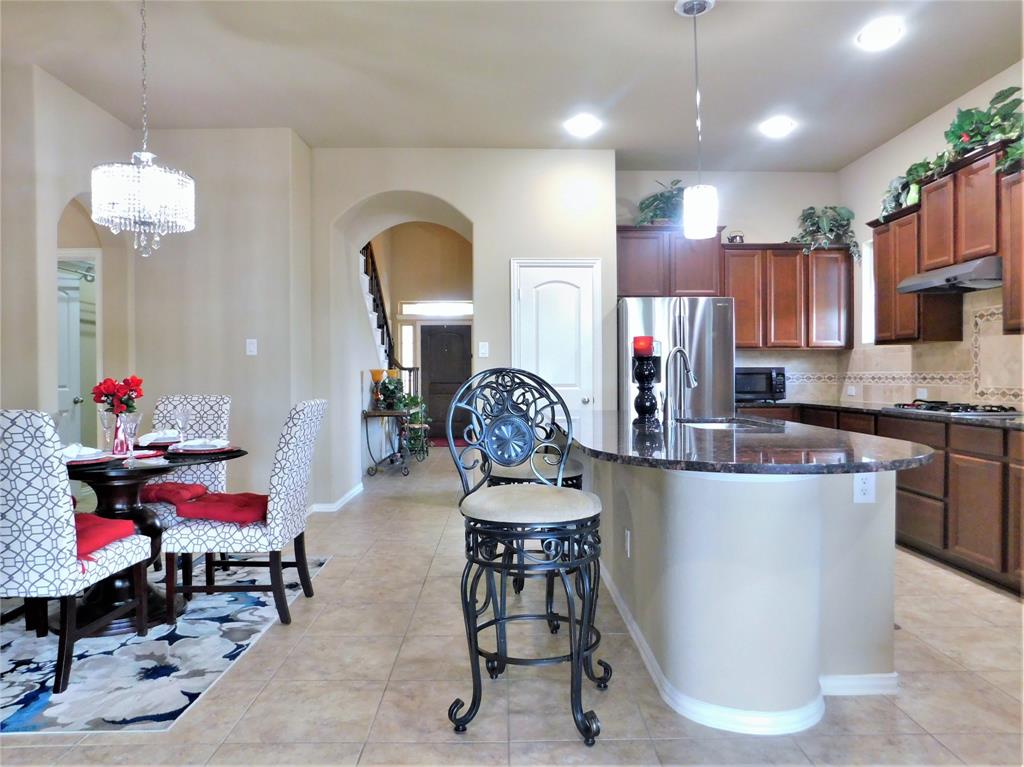 7712 Sweetgate Lane Denton, TX 76208 - Photo 9 of 40 a kitchen with stainless steel appliances kitchen island granite countertop a dining table chairs and a sink