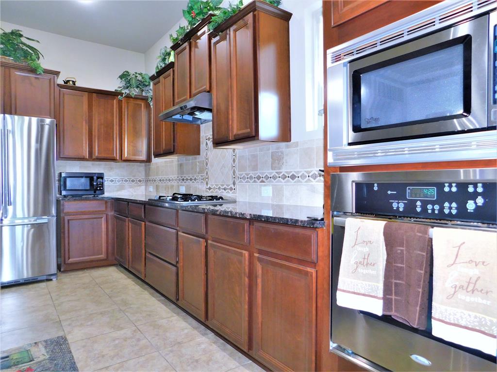 7712 Sweetgate Lane Denton, TX 76208 - Photo 10 of 40 a kitchen with stainless steel appliances granite countertop a sink stove and refrigerator