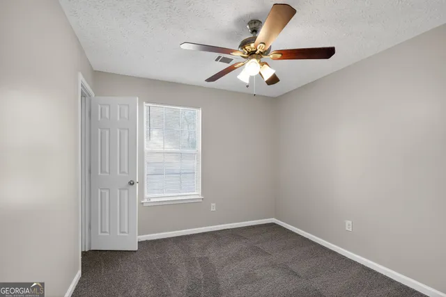 an empty room with windows and fan