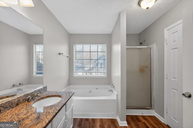 a bathroom with a granite countertop tub sink and mirror
