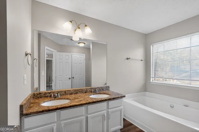 a bathroom with a granite countertop sink a large mirror and a bathtub