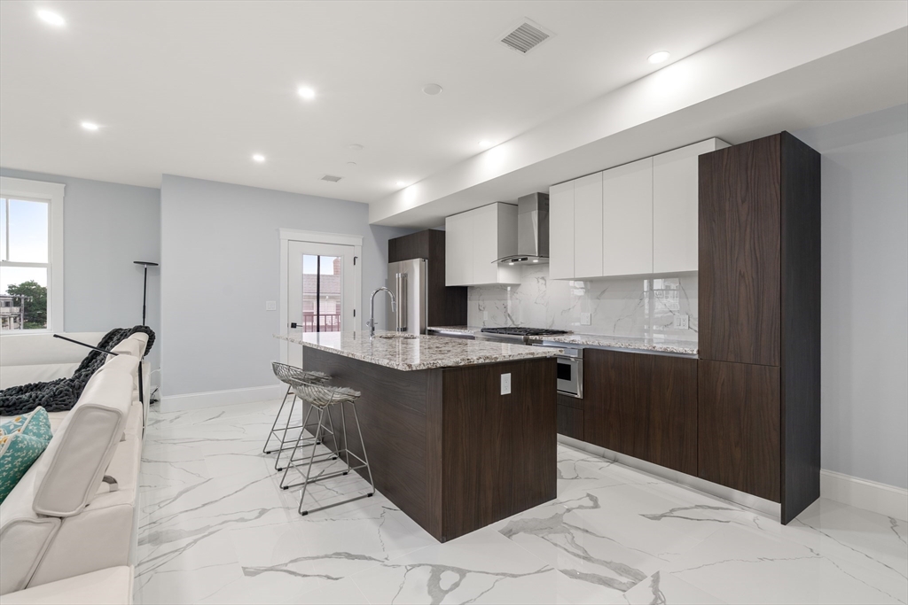 32 Pearl Street, Unit 4 Boston, MA 02125 - Photo 8 of 35 a large kitchen with kitchen island a sink counter space and stainless steel appliances