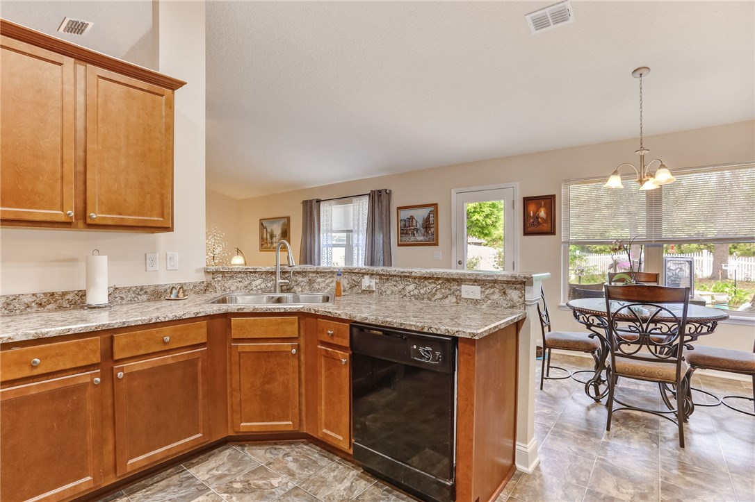 88156 Maybourne Road Yulee, FL 32097 - Photo 12 of 35 a open kitchen with granite countertop a stove a sink dishwasher and white cabinets with wooden floor