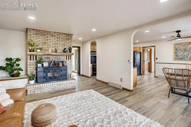 a large kitchen with stainless steel appliances kitchen island granite countertop a refrigerator a stove a sink a dining table and chairs with wooden floor