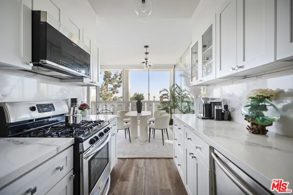 a kitchen with stainless steel appliances granite countertop white cabinets and a sink