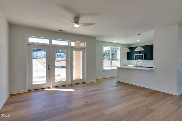 a view of an empty room with a kitchen and a window