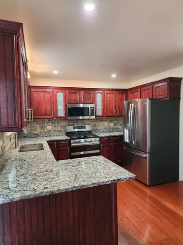 a kitchen with stainless steel appliances granite countertop a refrigerator a stove a sink and a microwave