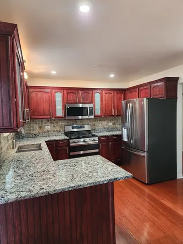 a kitchen with stainless steel appliances granite countertop a refrigerator a stove a sink and a microwave