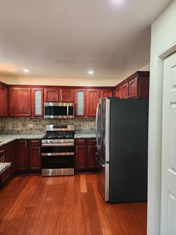 a kitchen with stainless steel appliances granite countertop a refrigerator and a stove top oven