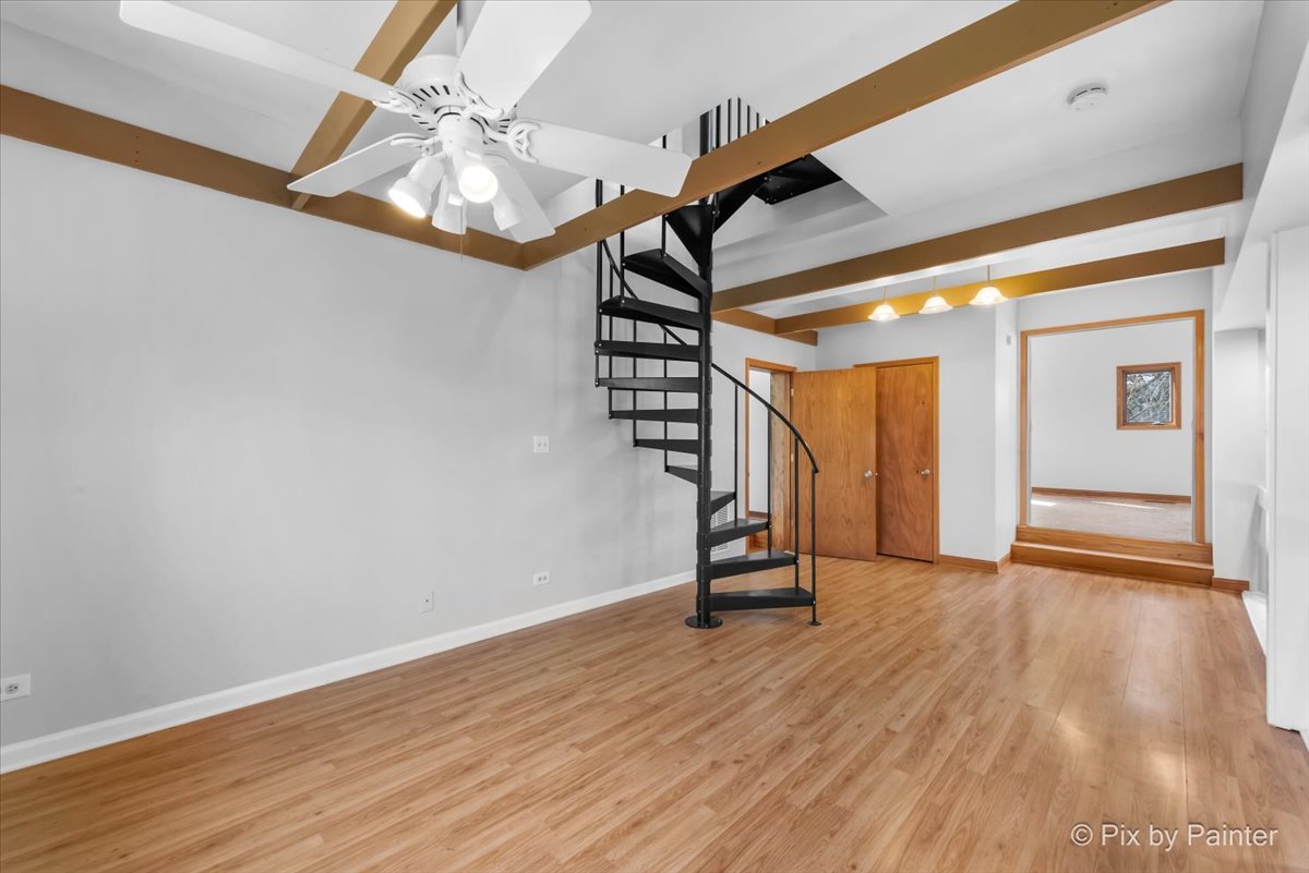 7611 Beverly Way Spring Grove, IL 60081 - Photo 19 of 33 a view of a room with wooden floor a ceiling fan and stairs
