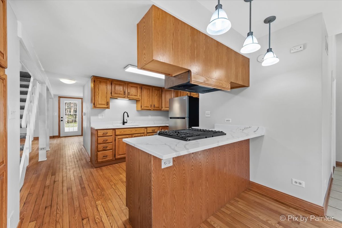 7611 Beverly Way Spring Grove, IL 60081 - Photo 6 of 33 a kitchen with stainless steel appliances a stove a sink and a wooden floor