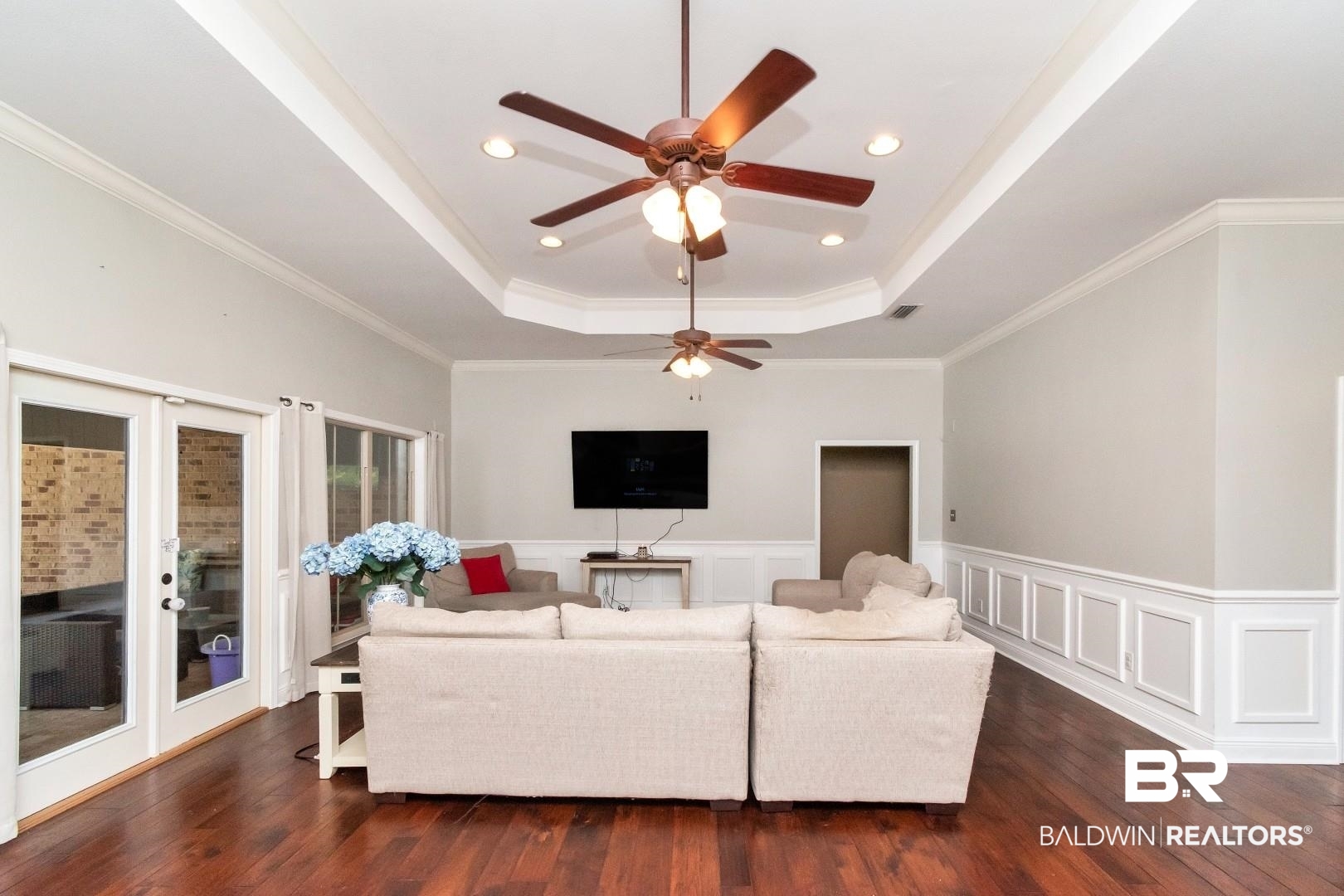 27890 Rileywood Drive Daphne, AL 36526 - Photo 6 of 49 Living area featuring french doors, a tray ceiling, dark wood-style flooring, wainscoting, and a ceiling fan