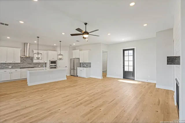 a large white kitchen with kitchen island a sink wooden floor and a refrigerator