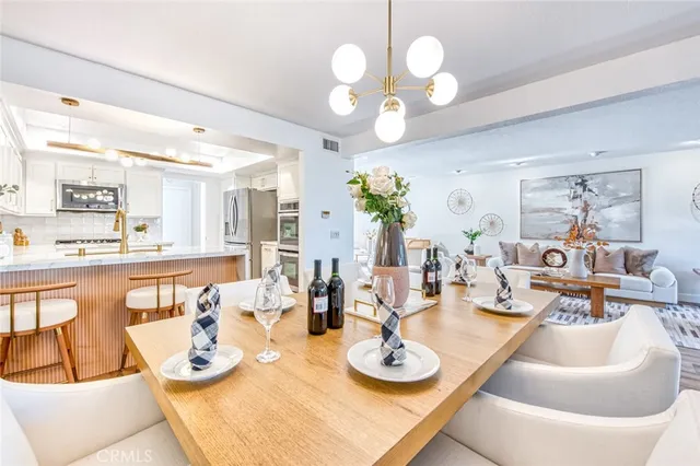 a view of a dining room and kitchen with furniture a chandelier and large window