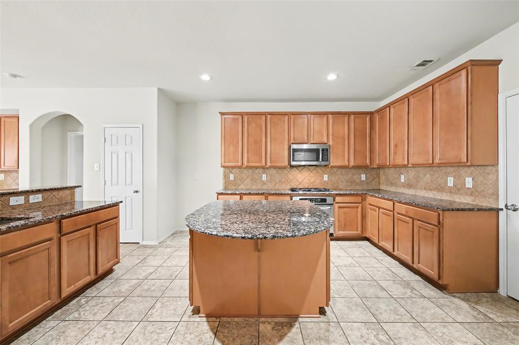 4902 Spring Lake Parkway Mansfield, TX 76063 - Photo 11 of 38 a large kitchen with granite countertop a sink dishwasher stove and cabinets