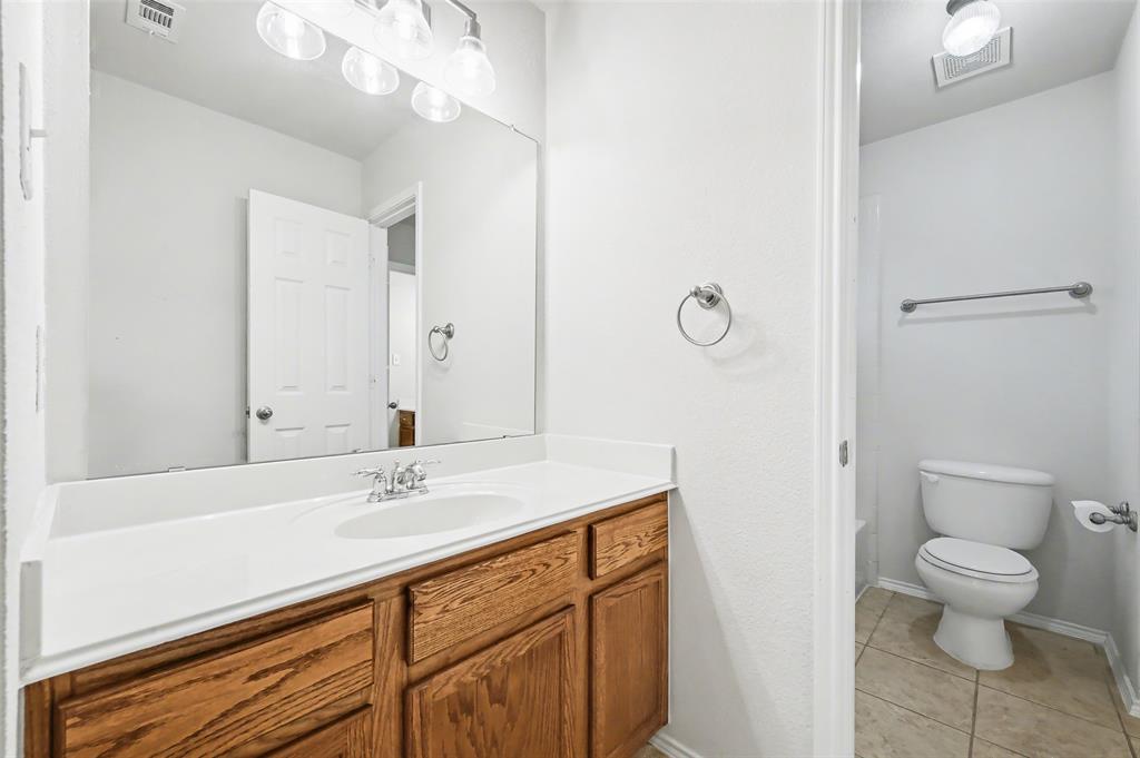 4902 Spring Lake Parkway Mansfield, TX 76063 - Photo 29 of 38 a bathroom with a sink a toilet and a large mirror