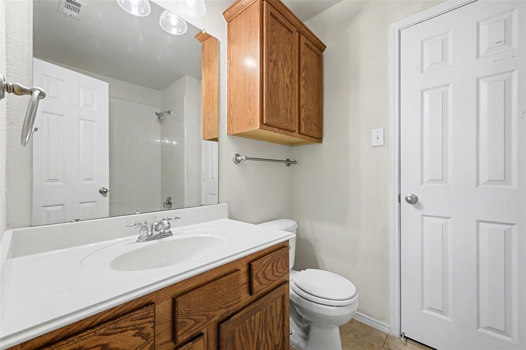4902 Spring Lake Parkway Mansfield, TX 76063 - Photo 32 of 38 a bathroom with a sink a toilet and a mirror