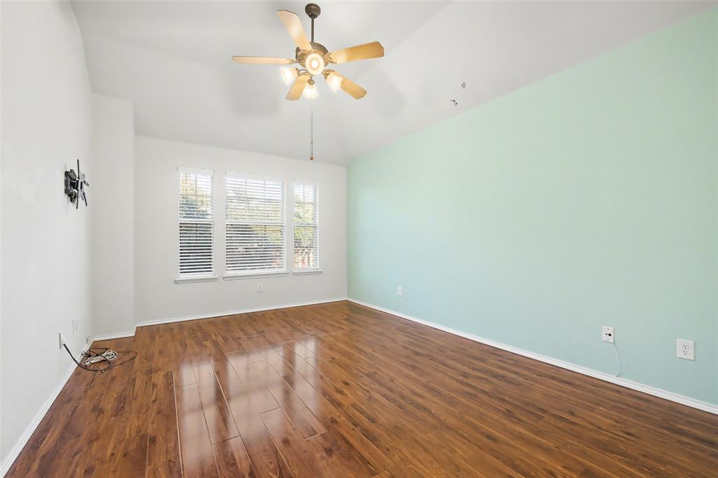 4902 Spring Lake Parkway Mansfield, TX 76063 - Photo 33 of 38 an empty room with wooden floor chandelier fan and windows