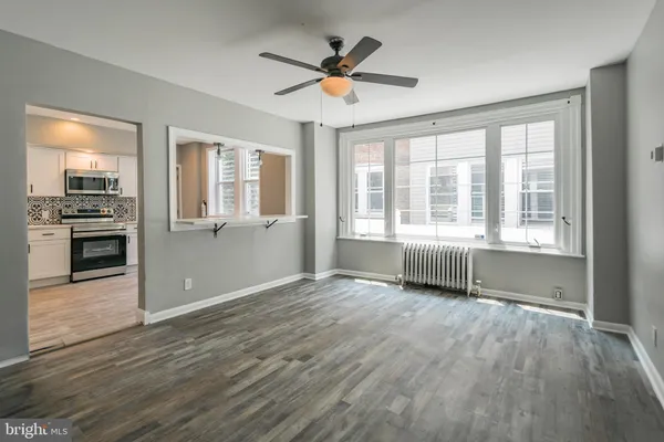 a view of an empty room with a kitchen and wooden floor