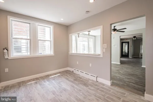 a view of empty room with wooden floor and fan