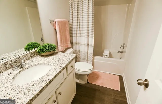 a bathroom with a granite countertop sink a toilet and shower