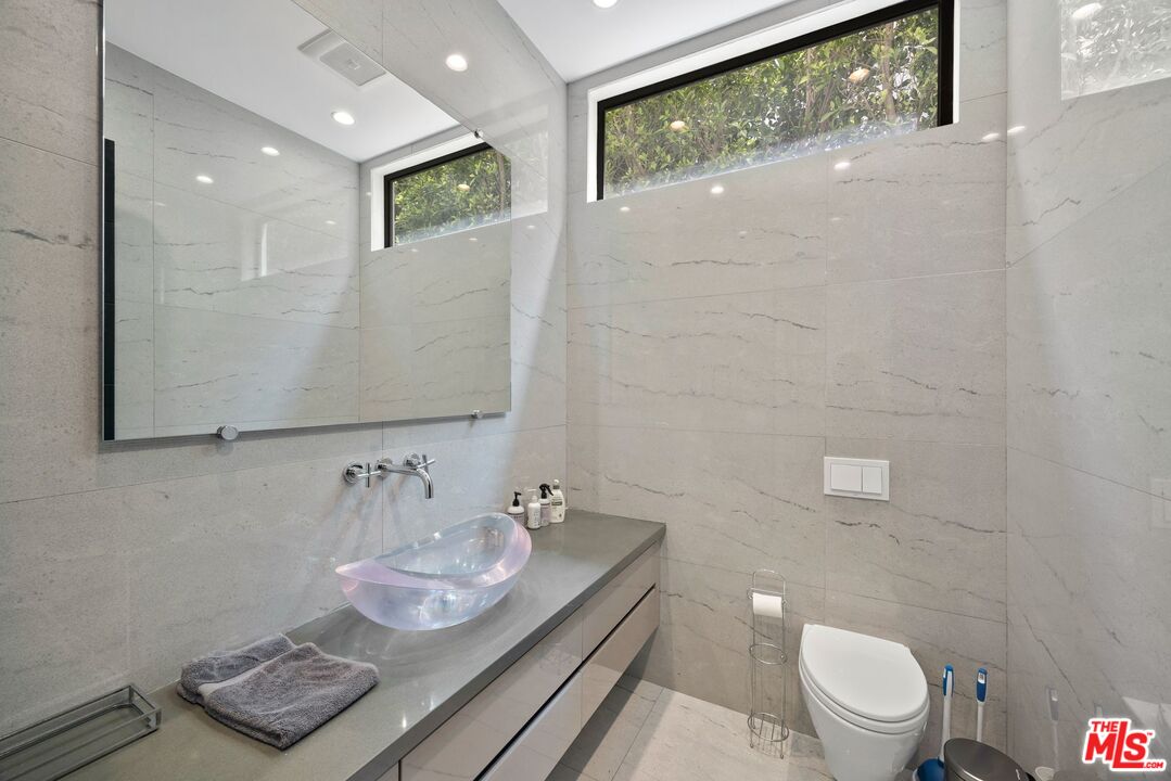 839 North Spaulding Avenue Los Angeles, CA 90046 - Photo 19 of 46 a bathroom with a granite countertop sink a toilet and a mirror