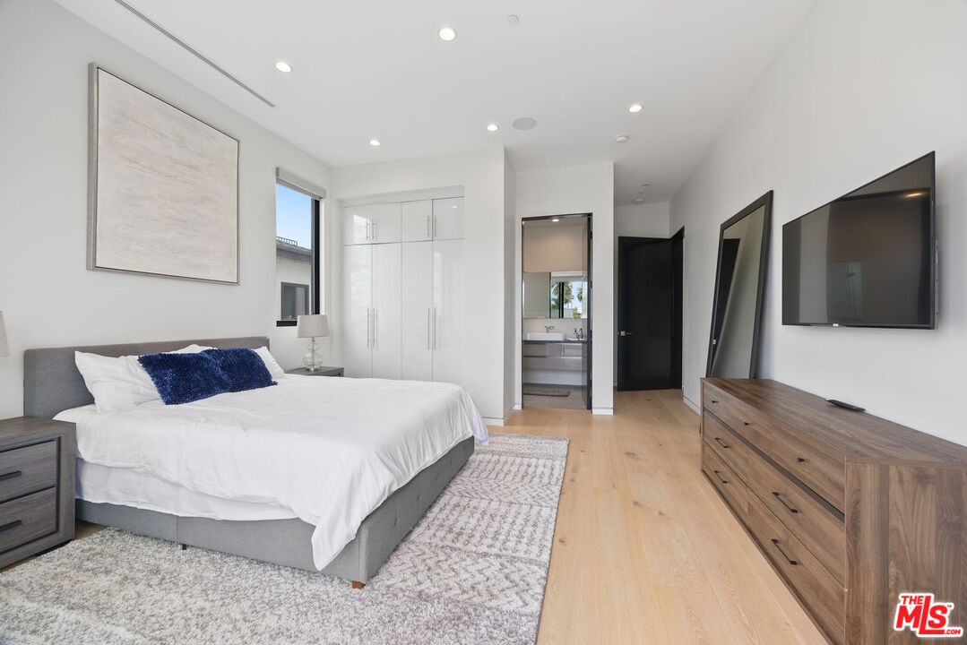 839 North Spaulding Avenue Los Angeles, CA 90046 - Photo 38 of 46 a spacious bedroom with a large bed a flat tv screen and a dresser