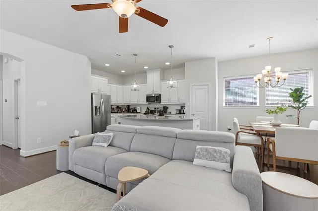 a living room with furniture kitchen view and a chandelier