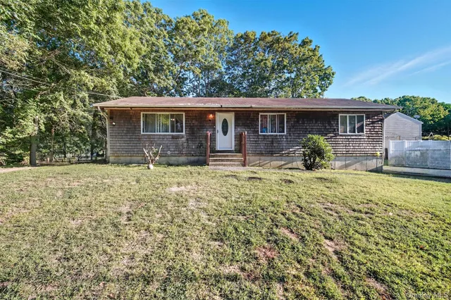 a front view of house with yard and trees in the background