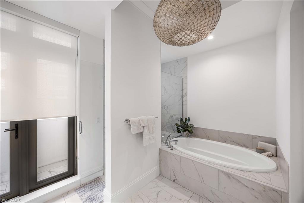 875 6th Avenue South, Unit 203 Naples, FL 34102 - Photo 10 of 49 Serene primary bathroom showcasing a walk-in shower and soaking tub for a spa-like experience.
