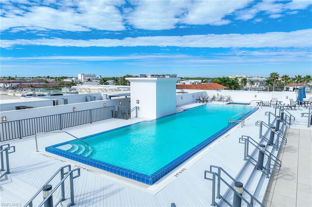 875 6th Avenue South, Unit 203 Naples, FL 34102 - Photo 13 of 49 Rooftop pool and hot tub offering a resort-style setting with lounge seating and views over downtown Naples.