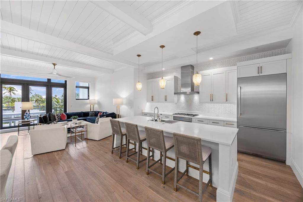 875 6th Avenue South, Unit 203 Naples, FL 34102 - Photo 49 of 49 Kitchen featuring a kitchen breakfast bar, stainless steel built in fridge, hanging light fixtures, open floor plan, and backsplash